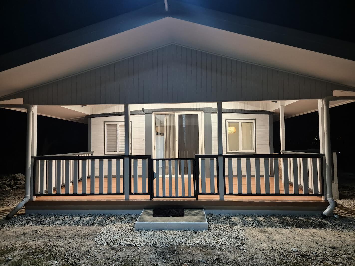 A modern compact single-storey home lit up at night on a NZ section