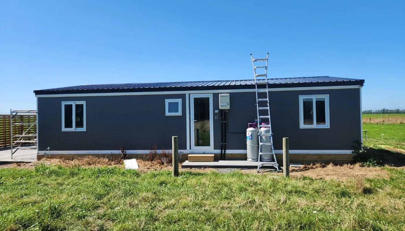 A grey Expanders® home installed on a rural site with services being connected