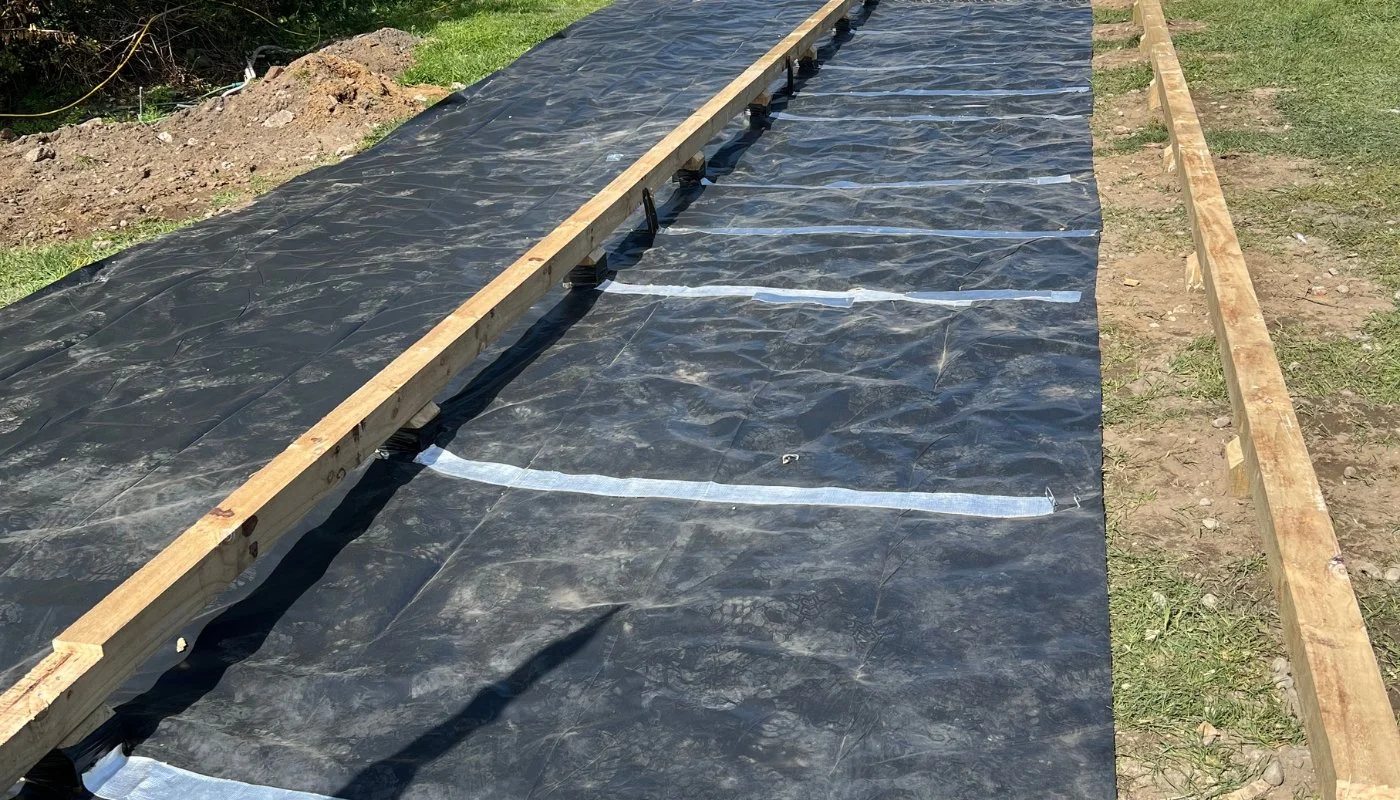 A prepared site base with ground sheeting, timber bearers and adjustable jacks ready for a tiny home