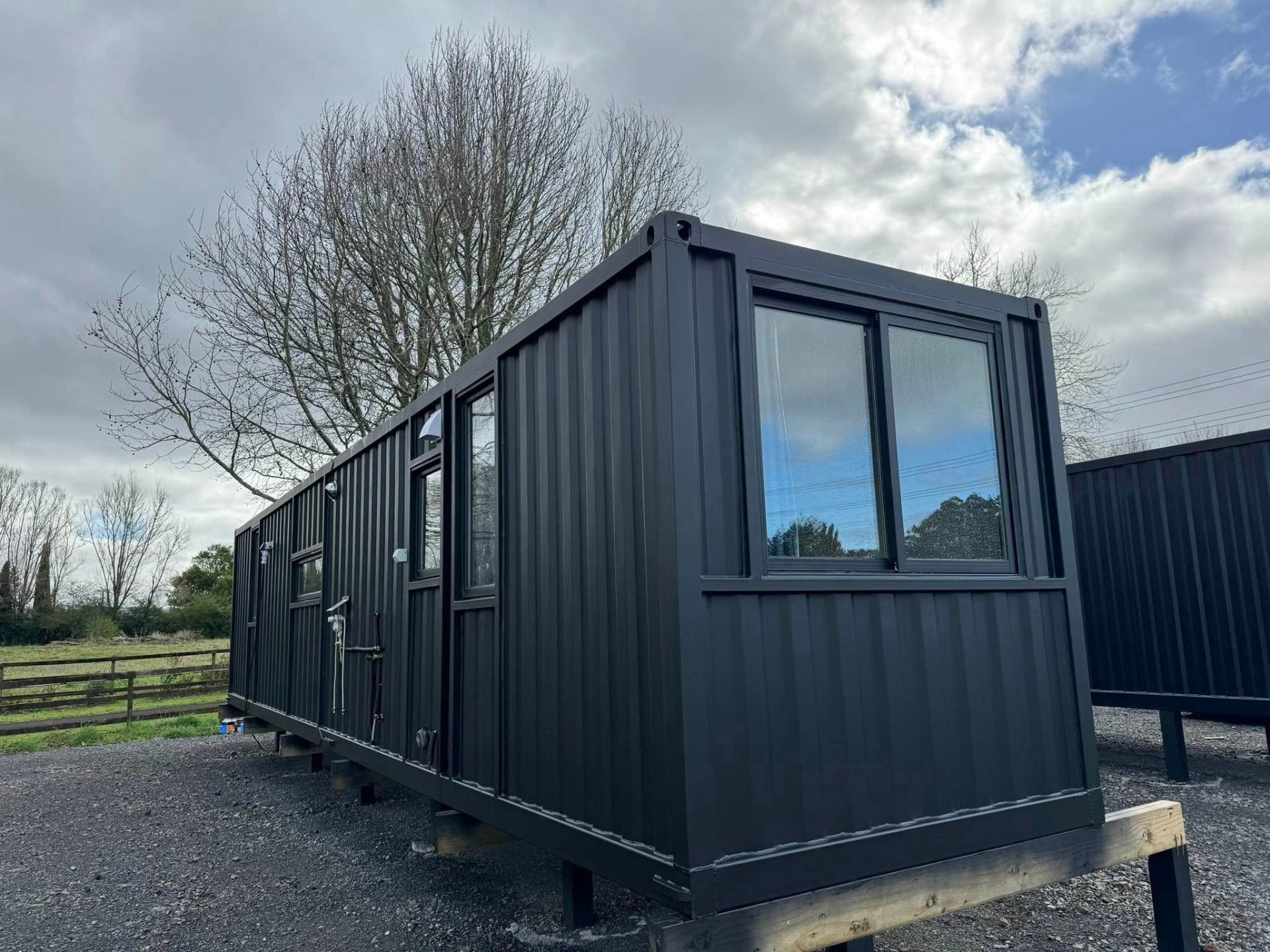 A dark-clad container-based tiny home on a rural NZ block