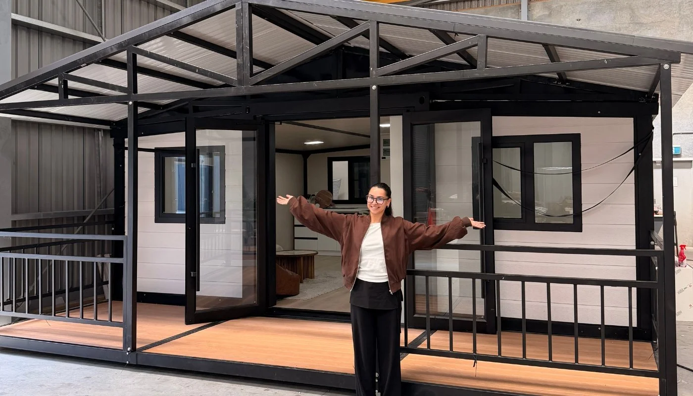 An upgraded black-framed expandable home with a covered deck inside the Expanders Christchurch warehouse