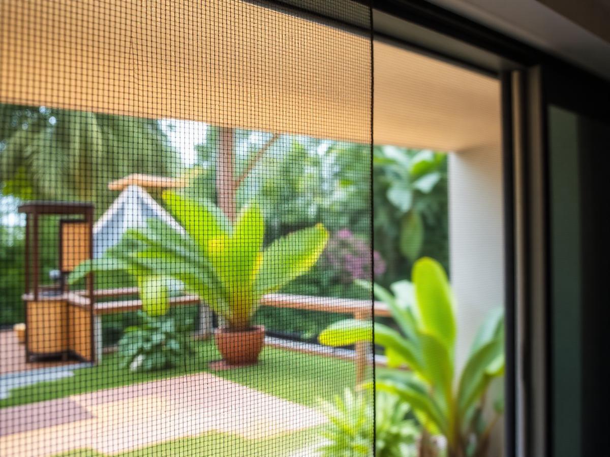 Close view of a fly screen fitted to a sliding door with tropical garden beyond